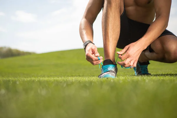 Deportista está atando cordones de zapatos en la hierba — Foto de Stock