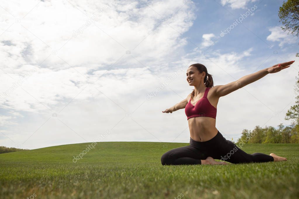 Smiling woman is training on green lawn