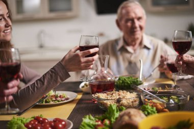 Kırmızı şarap yükselterek genç memnun kadın kontrolden kapatın. Aile ev pişmiş yemekte baba yanında oturuyor. Memnun ve gülümseyen kız