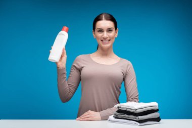 Çamaşırhane için deterjan gösteren çok mutlu ev kadını