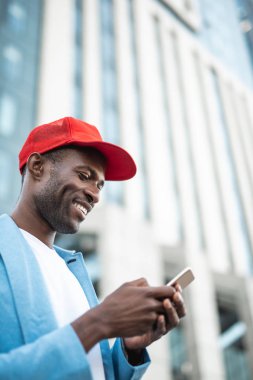 Erkek telefonunda Sokağı'nda bulunurken yazarak gülen düşük açılı yan görünüm