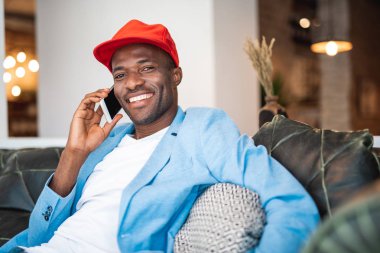 Erkek mobile tarafından konuşma rahat koltukta dinlenirken gülen portresi. Kameraya bakıyor