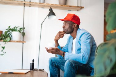 Yan görünümü dalgın adam içecek bir fincan tatma dinleniyor. El ile çene elinde