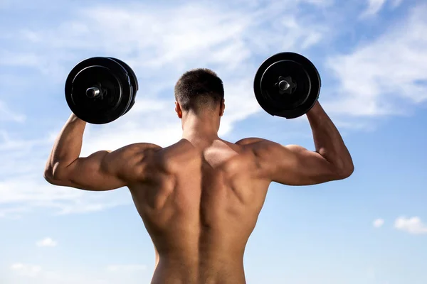 Strong athlete is lifting heavy outfit outdoors — Stock Photo, Image