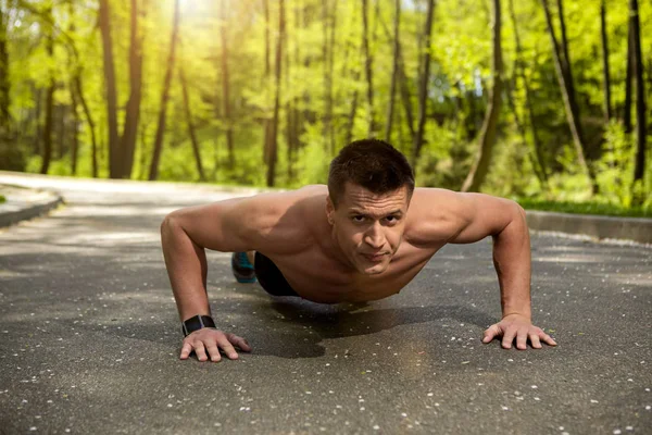 Musculoso hombre está haciendo flexiones en la madera — Foto de Stock