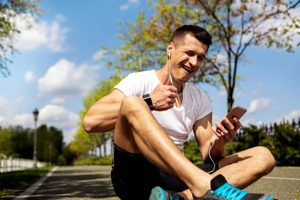 Atletisk man med enheter i blinkar och visar tummen upp — Stockfoto