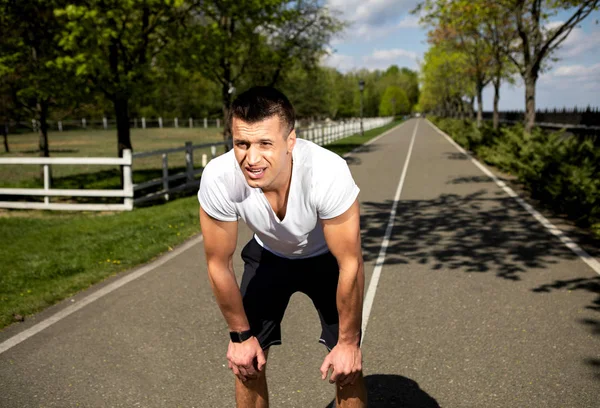 Fit hombre cansado está descansando durante la carrera en el campo — Foto de Stock