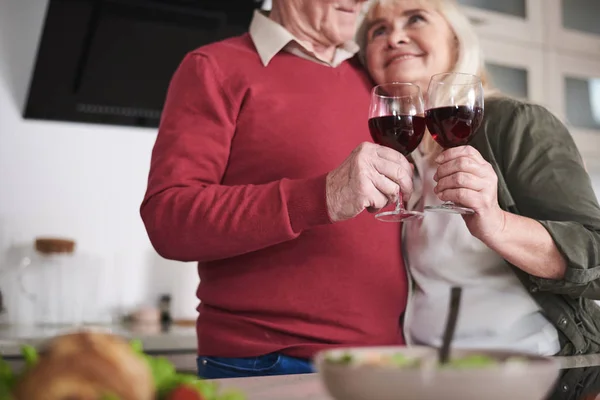Пожилые мужчины и женщины празднуют особое событие на кухне — стоковое фото