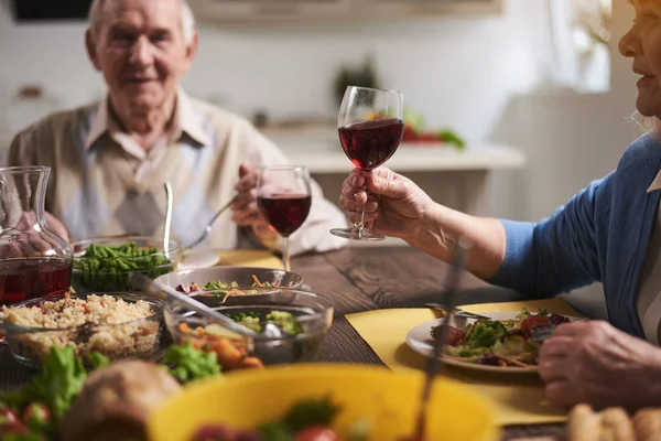 Radostné starší žena říká toasty k večeři — Stock fotografie