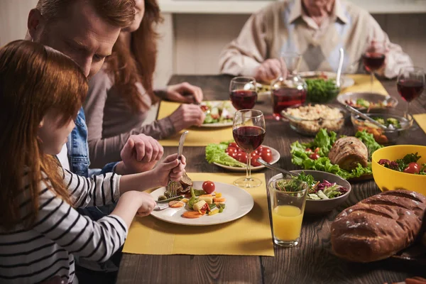 Klein meisje eten met familie thuis — Stockfoto