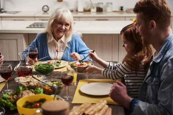 Χαμογελώντας ηλικιωμένη γυναίκα επικοινωνία στο δείπνο με την οικογένεια — Φωτογραφία Αρχείου