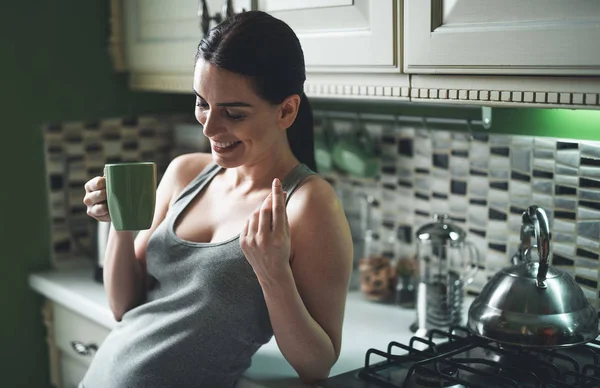 Усміхнена жінка п'є гарячий напій перед сніданком — стокове фото