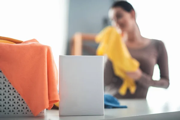 Detergente para roupas sujas em pé na mesa perto da mulher — Fotografia de Stock