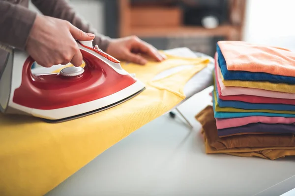 Mulher passando roupas coloridas em casa — Fotografia de Stock