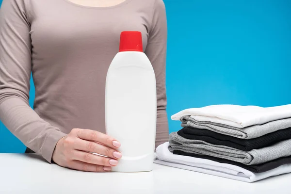 Mujer sosteniendo detergente en un montón de ropa — Foto de Stock