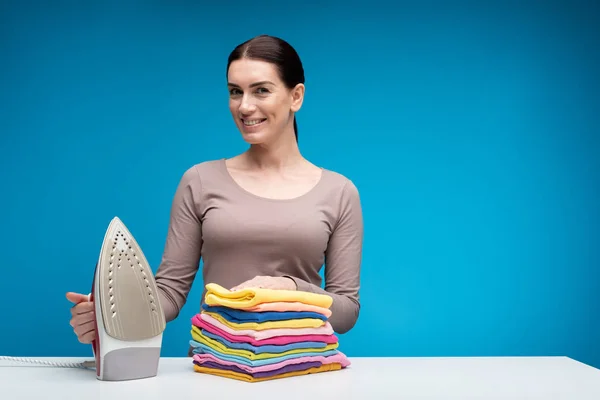 Mulher feliz em pé à mesa com lavanderia limpa — Fotografia de Stock