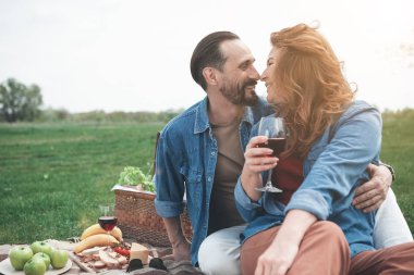 Neşeli aşıklar şarap ile çayır üzerinde rahatlatıcı 