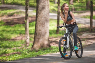 Çekici kadın Bisiklete binme sırasında telefonla konuşuyor