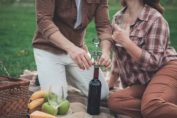 Homem abrindo bebida alcoólica por garrafa-parafuso perto da mulher — Fotografia de Stock