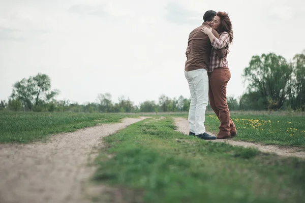 Tillgiven mannen och kvinnan krama på ängen väg — Stockfoto