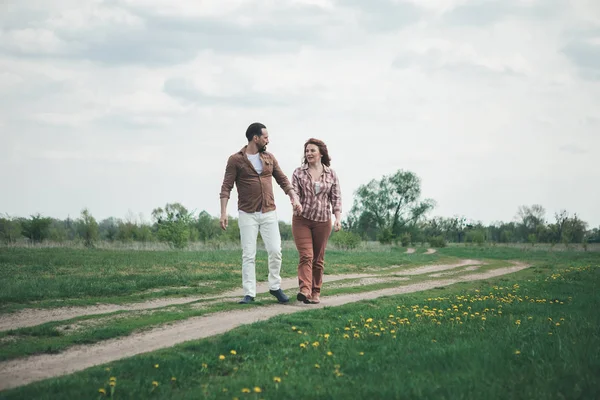 Счастливые мужчина и женщина наслаждаются романтической прогулкой по цветочному лугу — стоковое фото