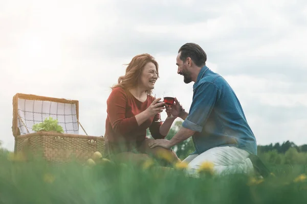 Joyful husband and wife drinking wine on meadow — Stock Photo, Image