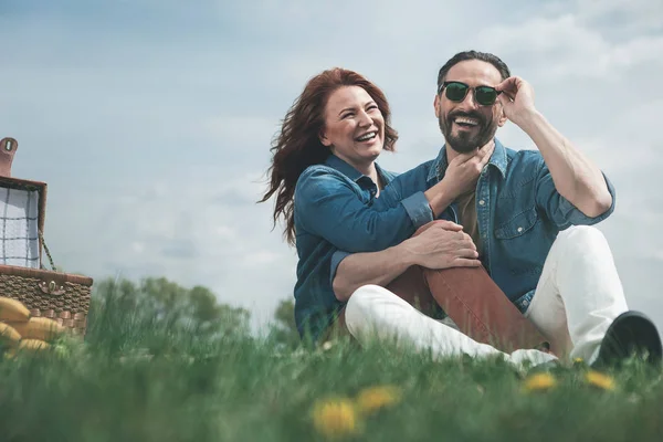 Vrolijke echtpaar hebben picnic op grasland — Stockfoto