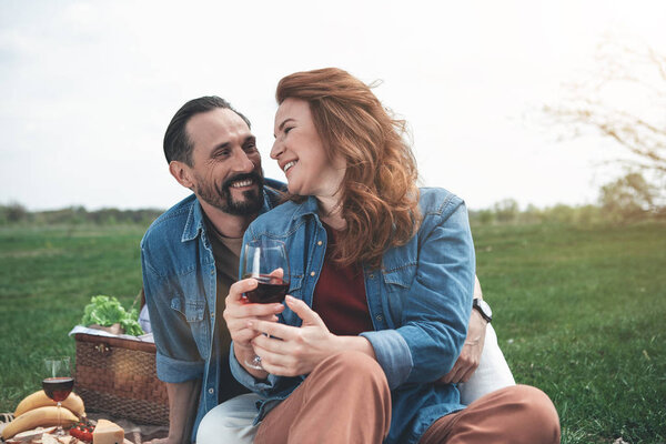 Happy loving couple sitting on blanket in the nature 