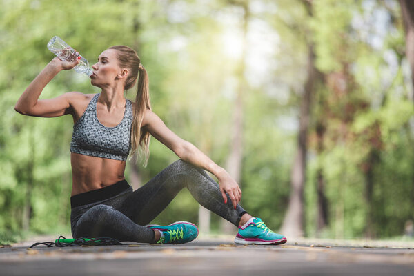 Sporty woman is drinking water outside