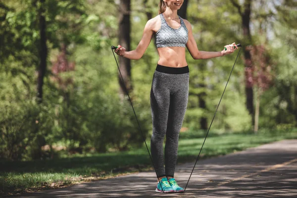Mujer feliz está entrenando con saltar la cuerda afuera —  Fotos de Stock