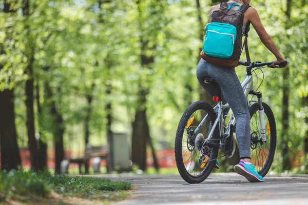 Атлетическая леди путешествует на велосипеде среди зеленых деревьев — стоковое фото