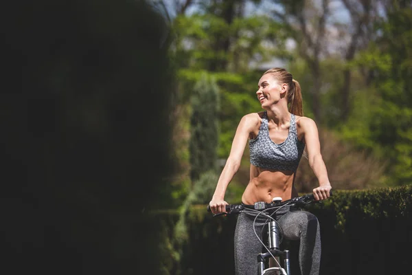 Mujer alegre es el ciclismo entre el césped — Foto de Stock