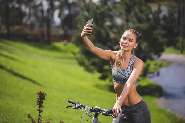 Sourire fille sur vélo prend selfie — Photo