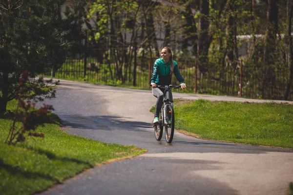 Ухмыляющаяся юная леди катается на велосипеде в парке — стоковое фото