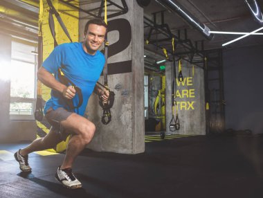 Süspansiyon kablosuyla egzersiz yapan neşeli erkek