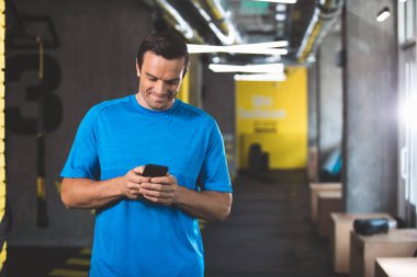 Neşeli erkek spor salonunda telefon kullanma