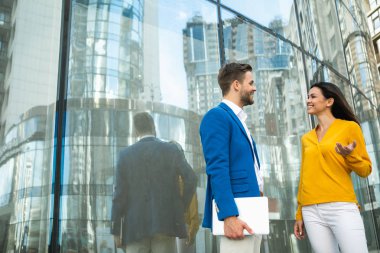 Mutlu iki meslektaş ofis binası yakınındaki açık iletişim programlarıdır. Onlar gesticulating ve gülüyor. Adam dizüstü kolundan tutuyor. Kopya alanı 