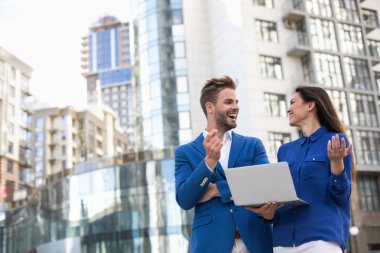 Sokakta dizüstü kullanarak neşeli iş ortakları 