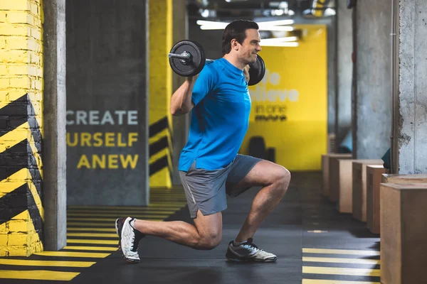 Beaming male making exercise in fitness center