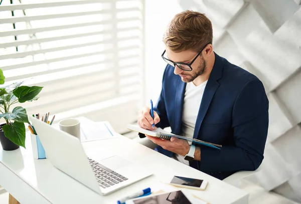 Upptagen man att göra anteckningar på jobbet — Stockfoto