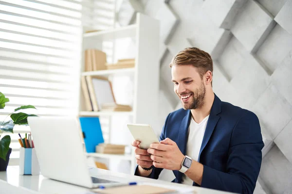 Uomo sorridente che tiene tablet in carica — Foto Stock