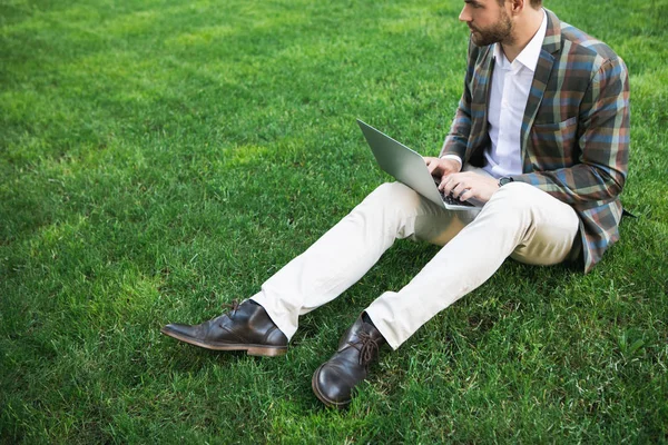 Dalgın işadamı laptop çimlerin üzerine yazarak 