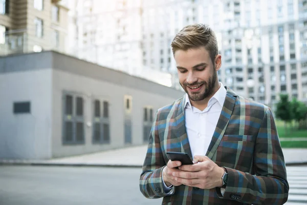 Gioioso uomo d'affari che utilizza il telefono cellulare sulla strada — Foto Stock