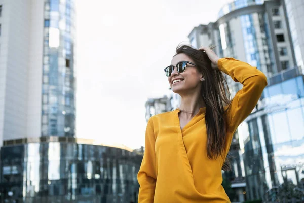 Mujer de negocios alegre de pie en la calle cerca de edificios de oficinas —  Fotos de Stock