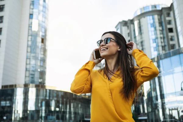 Mujer joven emocionada hablando por teléfono inteligente en la ciudad — Foto de Stock