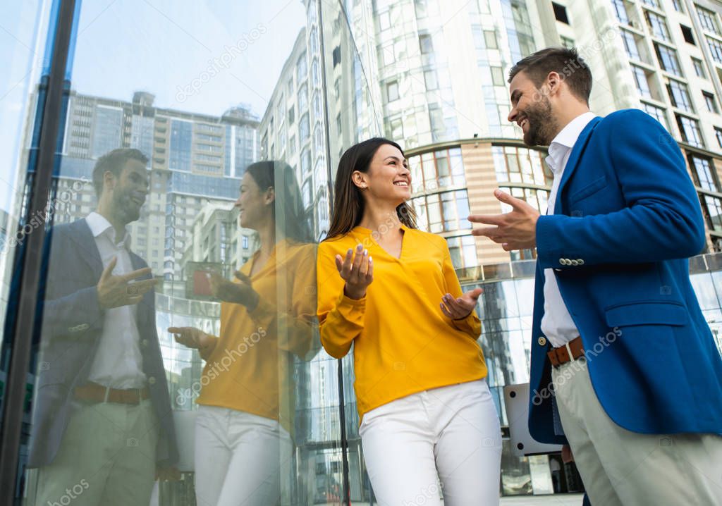 Cheerful colleagues talking near business center 