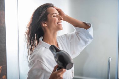 Neşeli erkek becerikli alet ile saç kurutma