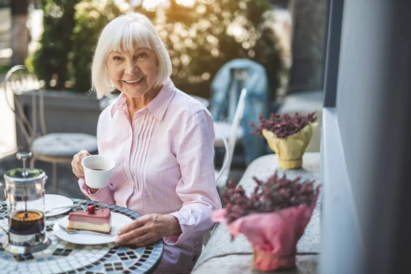 Smiling elderly woman enjoying tea outdoors — Stock Photo, Image