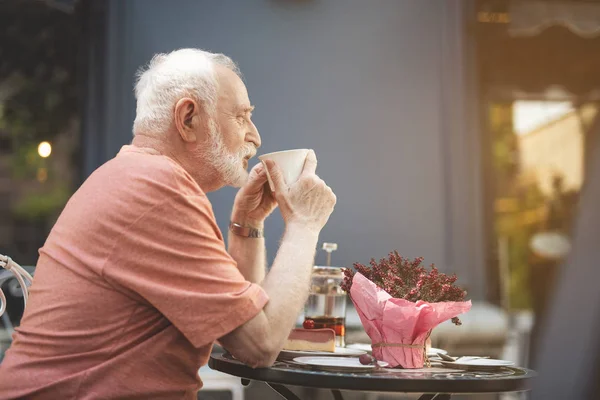 Viejo tomando una bebida caliente en la cafetería afuera — Foto de Stock