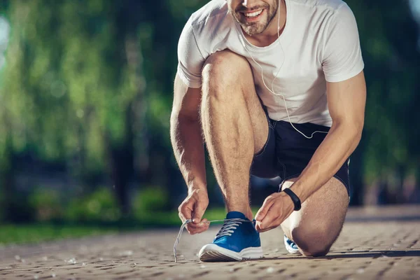 Щасливий чоловік фіксує шнурки під час тренувань — стокове фото